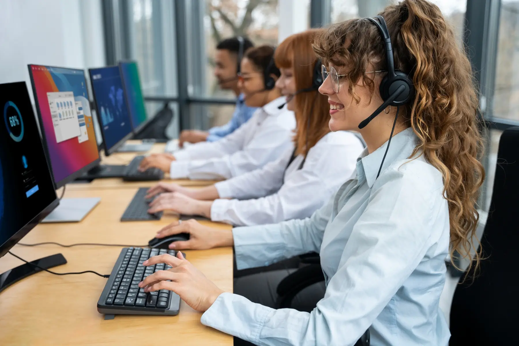 four people working at a desk with headsets on