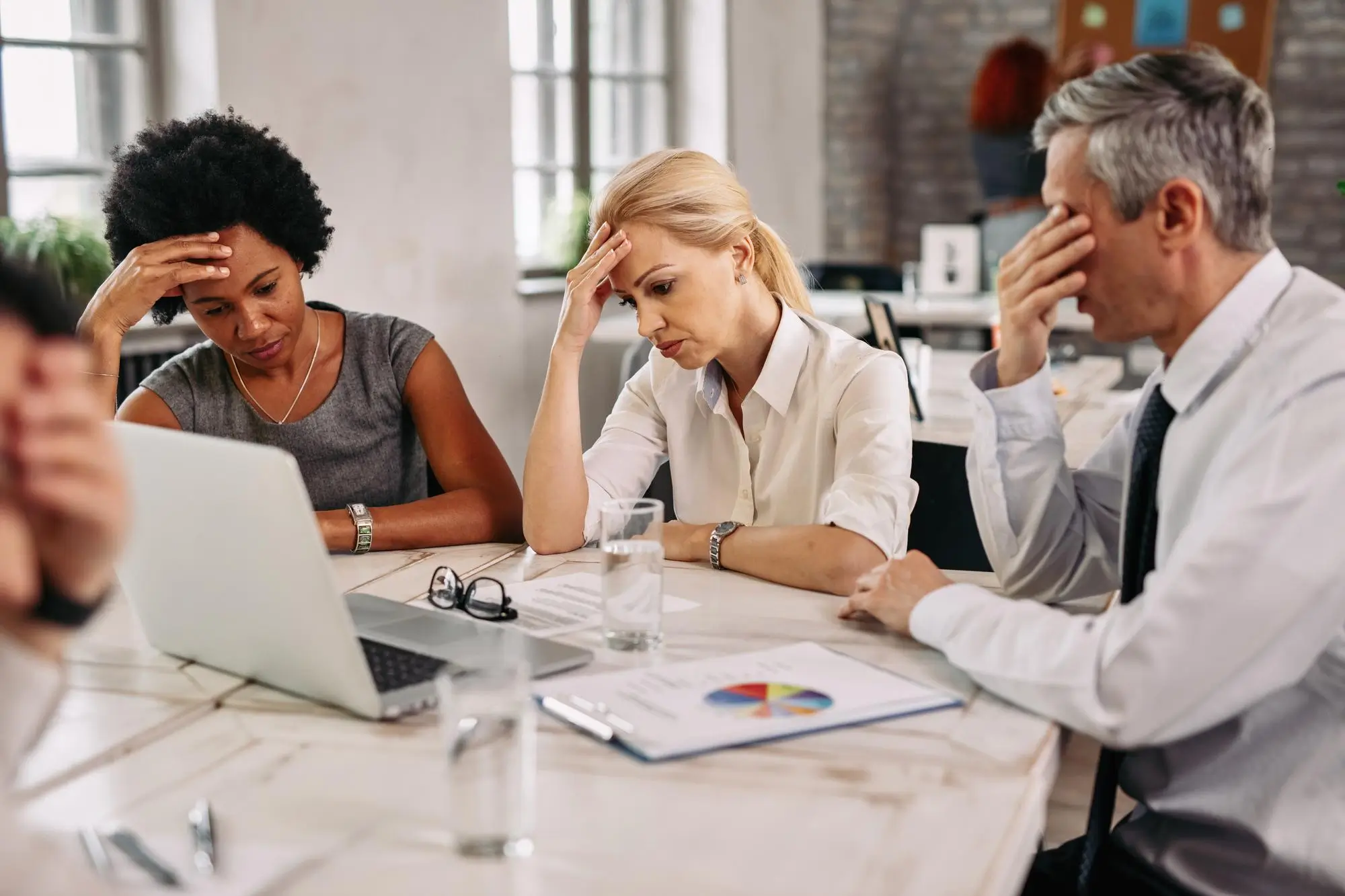 three people thinking deeply sitting at desk in front of a computer